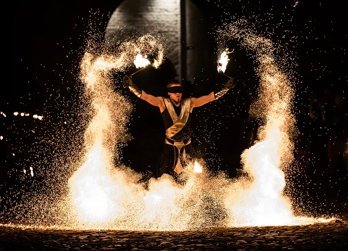 Two masked performers create interlocking rings of fire