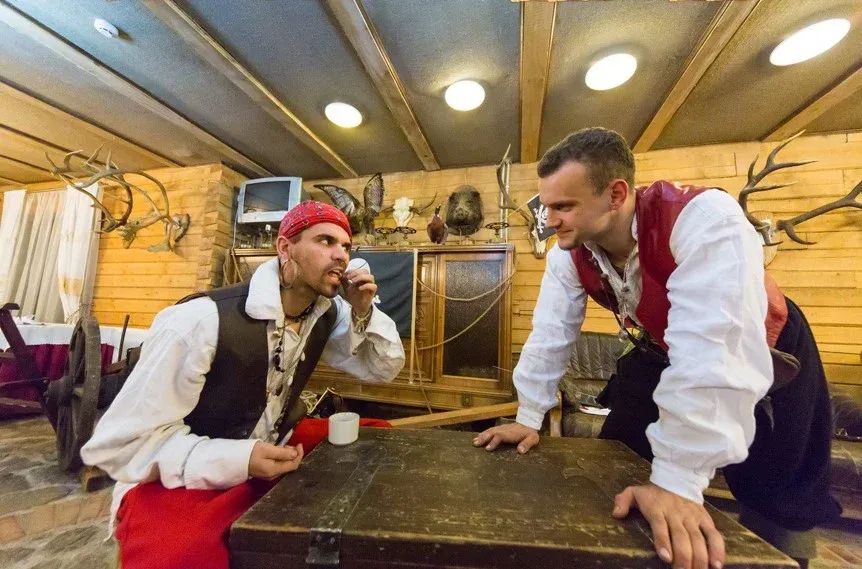 Piratų personažų pora su taurėmis rankose vakarėlio scenoje