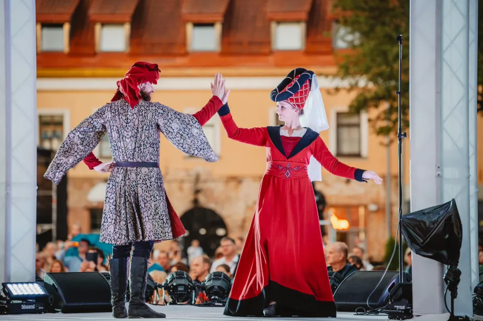 Para tańczy na scenie w wieczornym oświetleniu przed publicznością