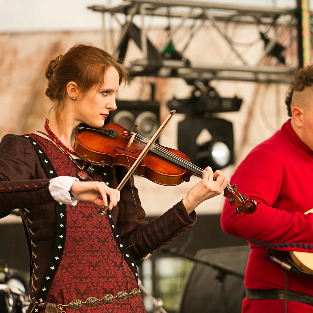 A violinist performs on stage alongside a bandmate