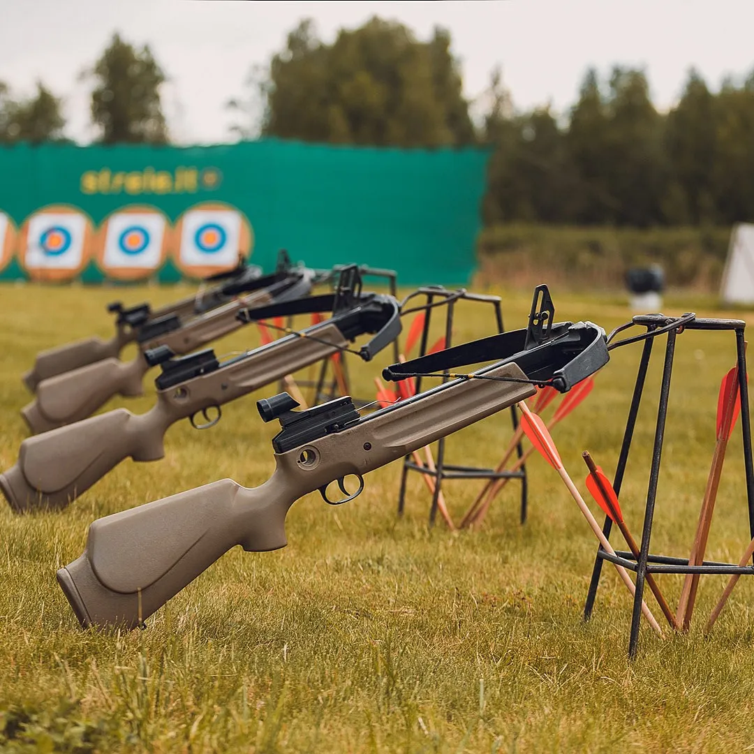 A row of crossbows mounted on stands at a shooting range