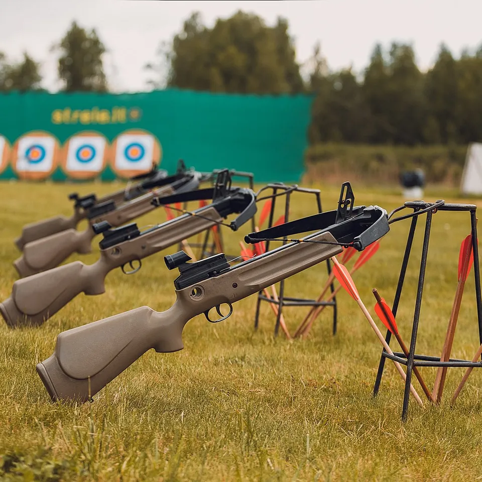 A row of crossbows mounted on stands at a shooting range