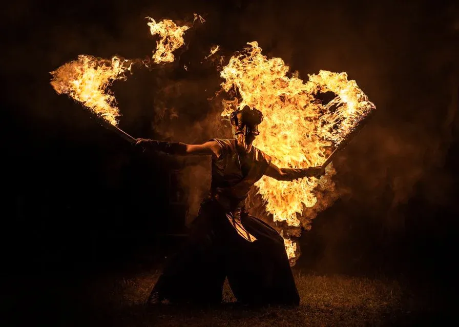 A performer spins a blazing fire staff in the darkness