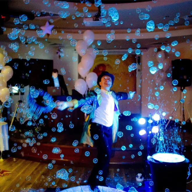 Bubble show at an indoor birthday party with balloons and blue lighting