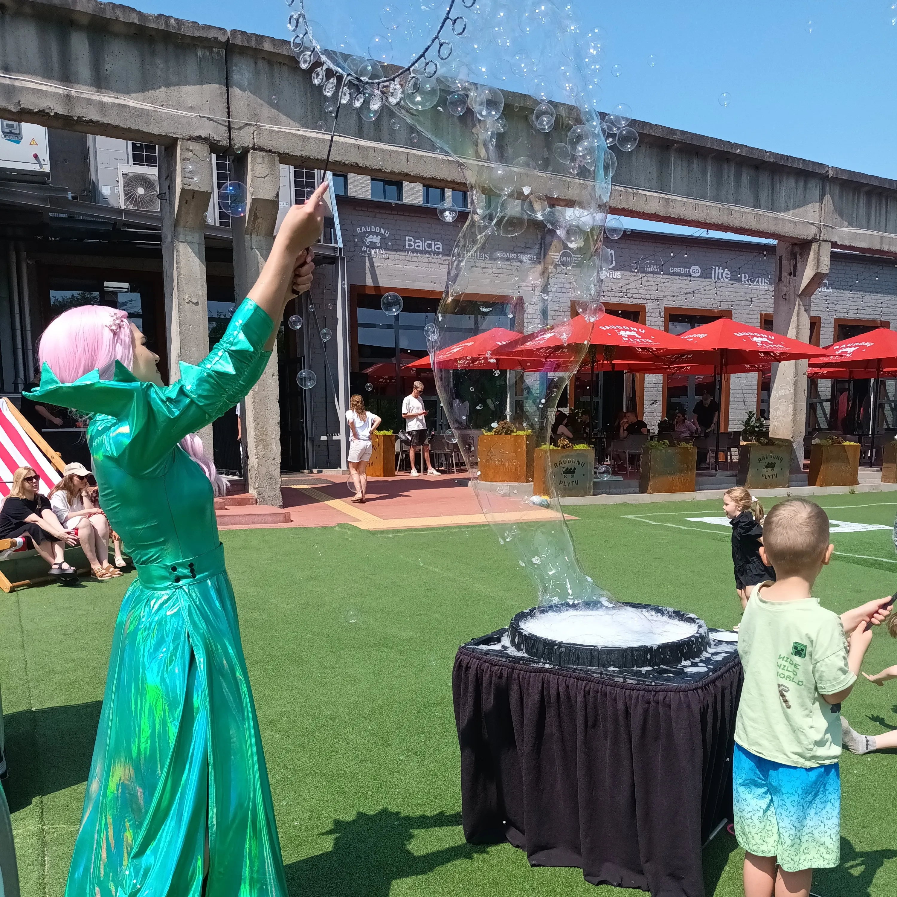Bubble show on an outdoor café terrace with children and a large bubble