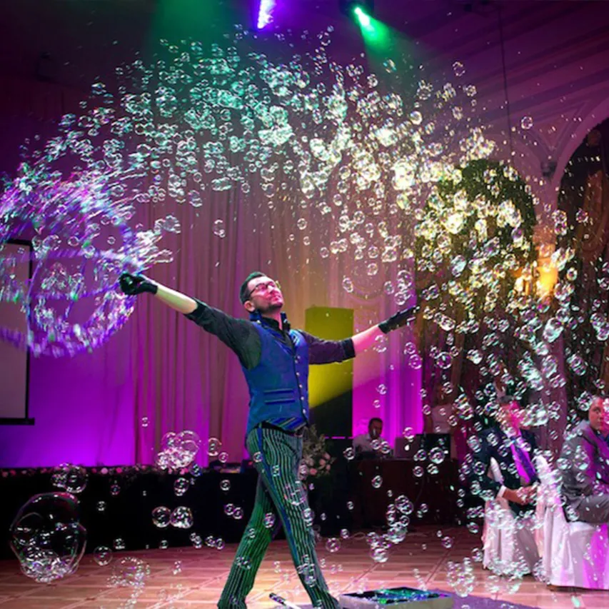 A bubble illusionist on stage surrounded by hundreds of bubbles in colorful light