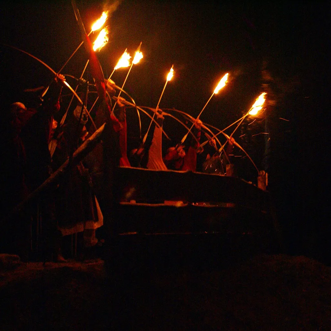 Archer silhouettes shoot flaming arrows during a night performance