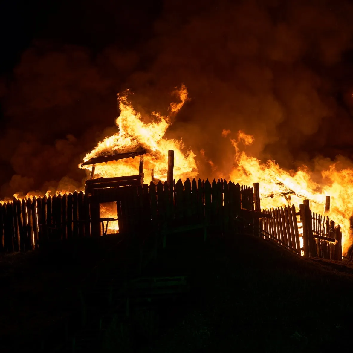 A wooden structure engulfed in flames as part of a night-time show