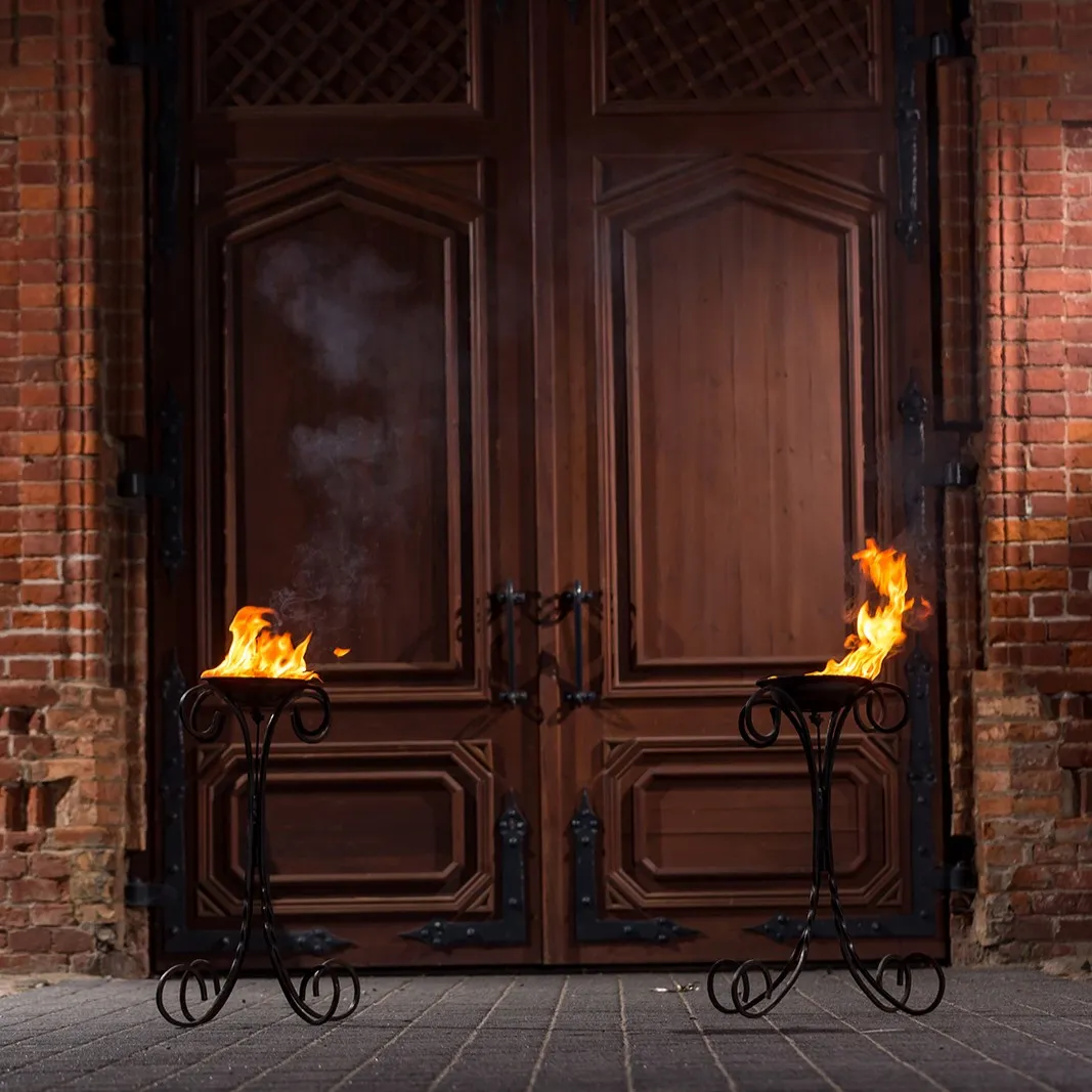 Two fire stands flank an ornate set of double doors symmetrically