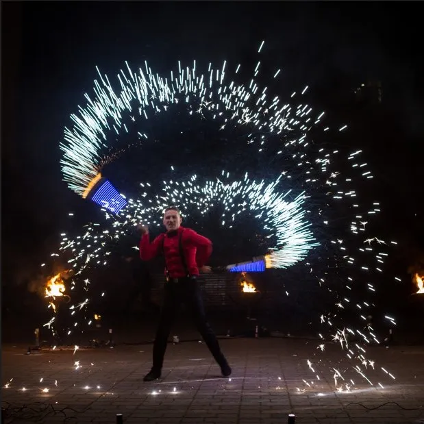 A performer with LED batons in the middle of a ring of sparks