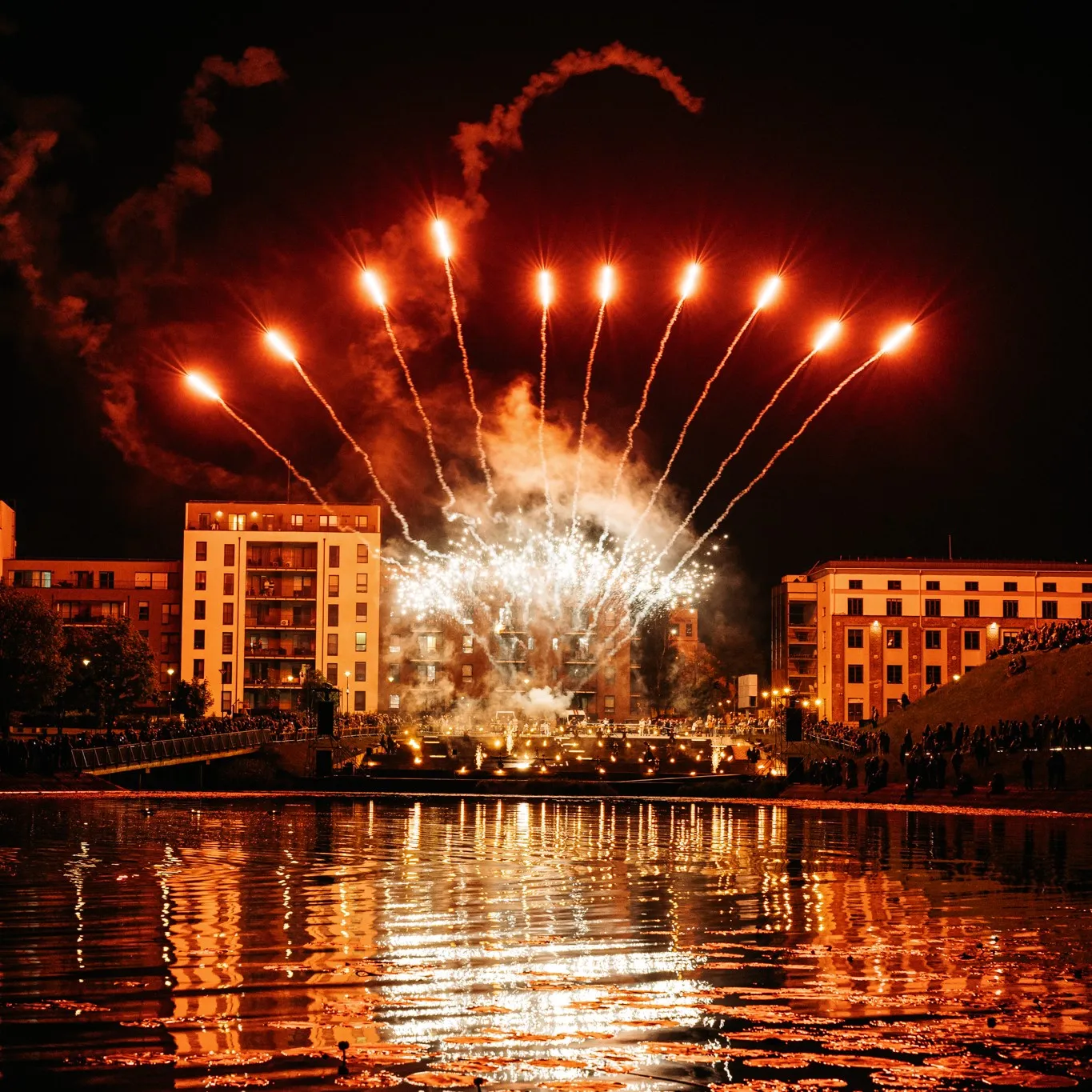 Fireworks light up above a city riverbank during the performance