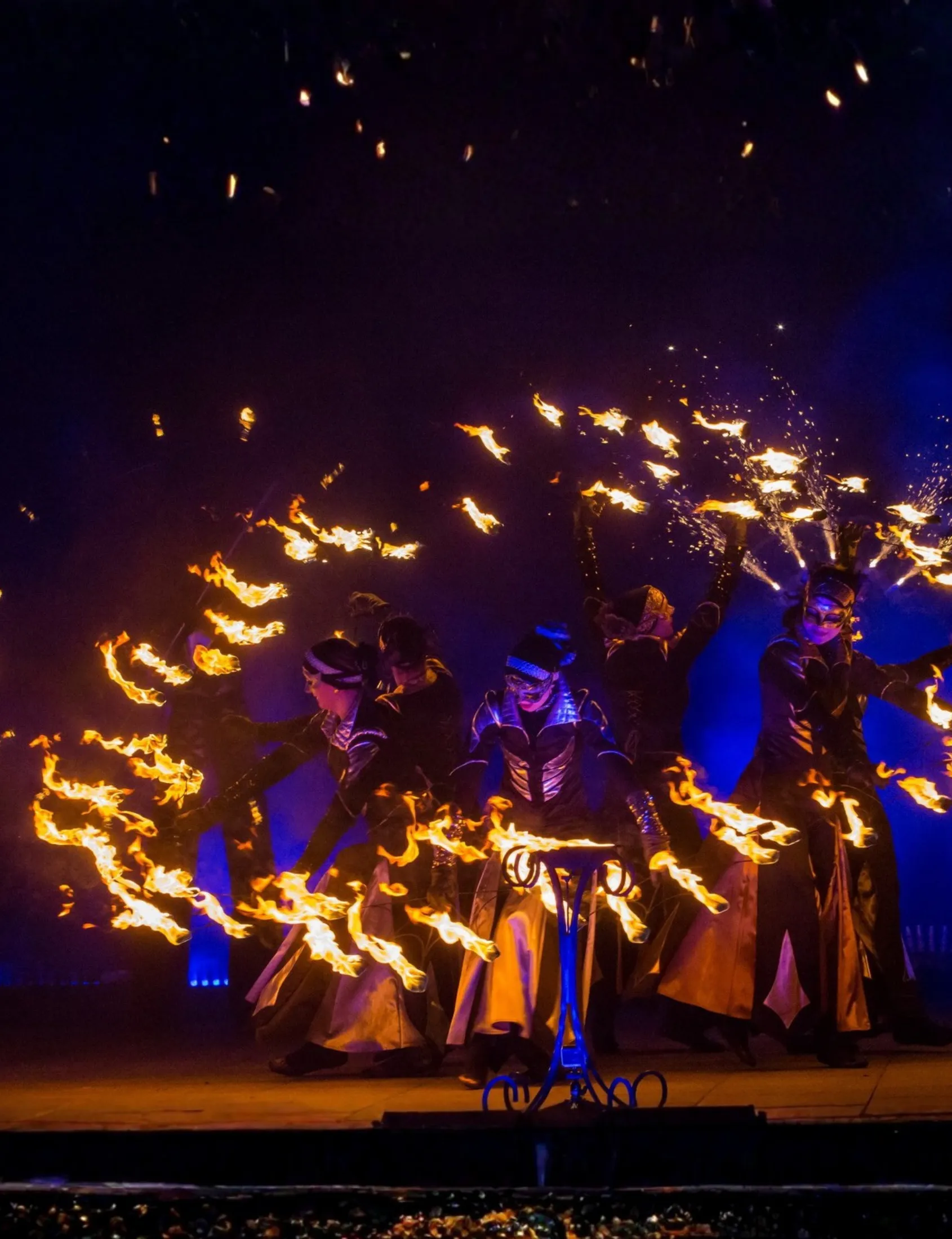A group of fire performers with blazing tools on stage