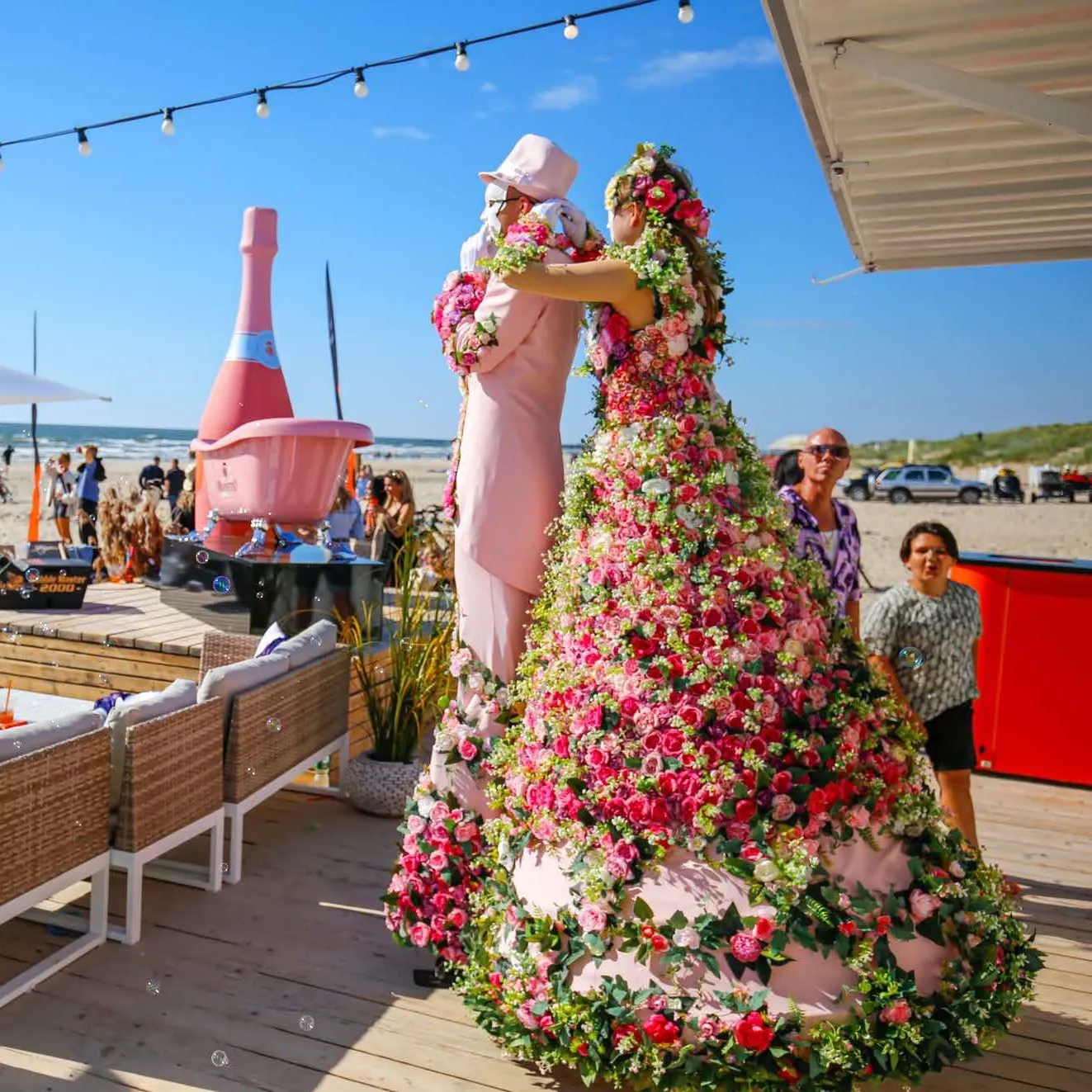 Flower characters on stilts embracing at a beach party