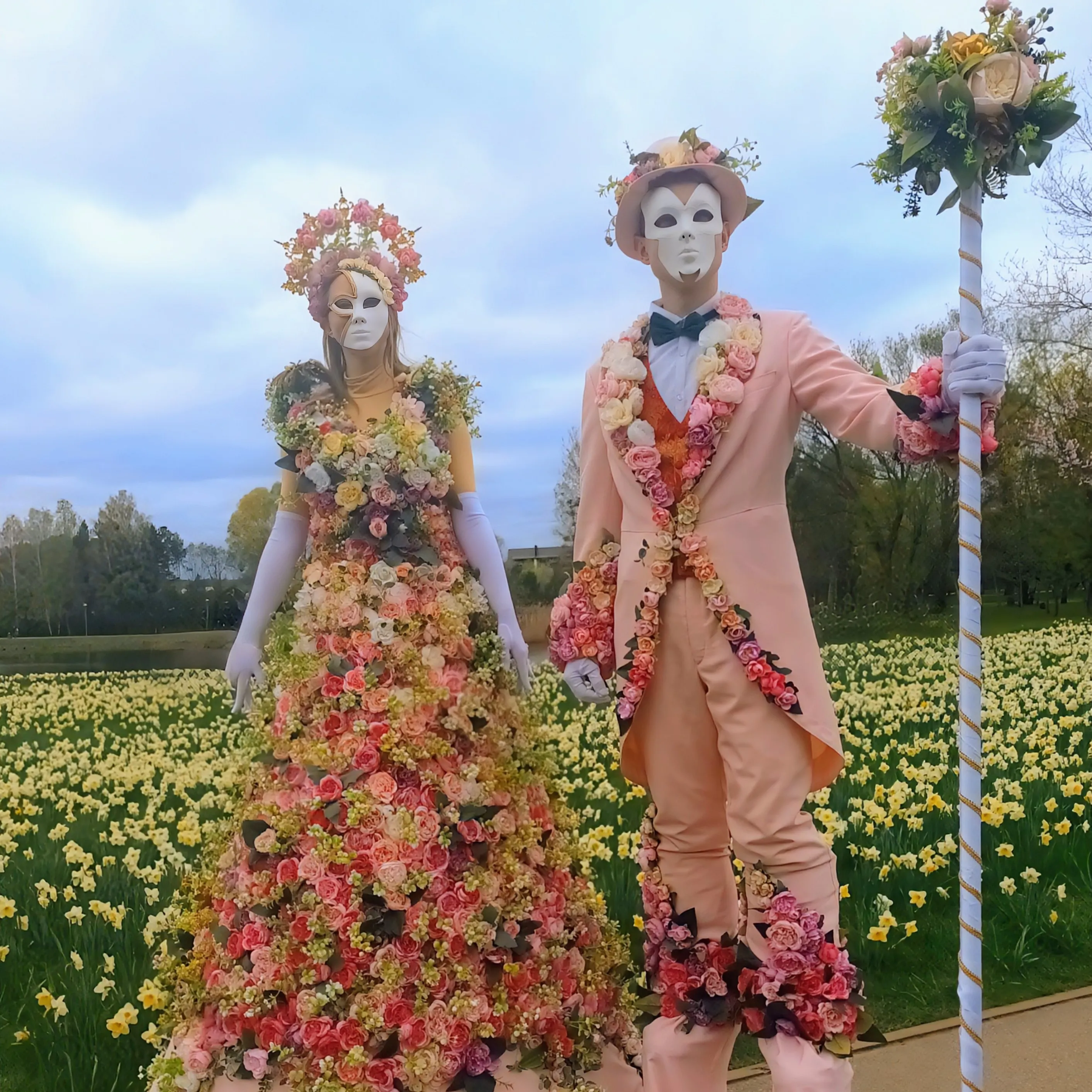 Flower people couple standing in a field of blooming daffodils wearing floral crowns