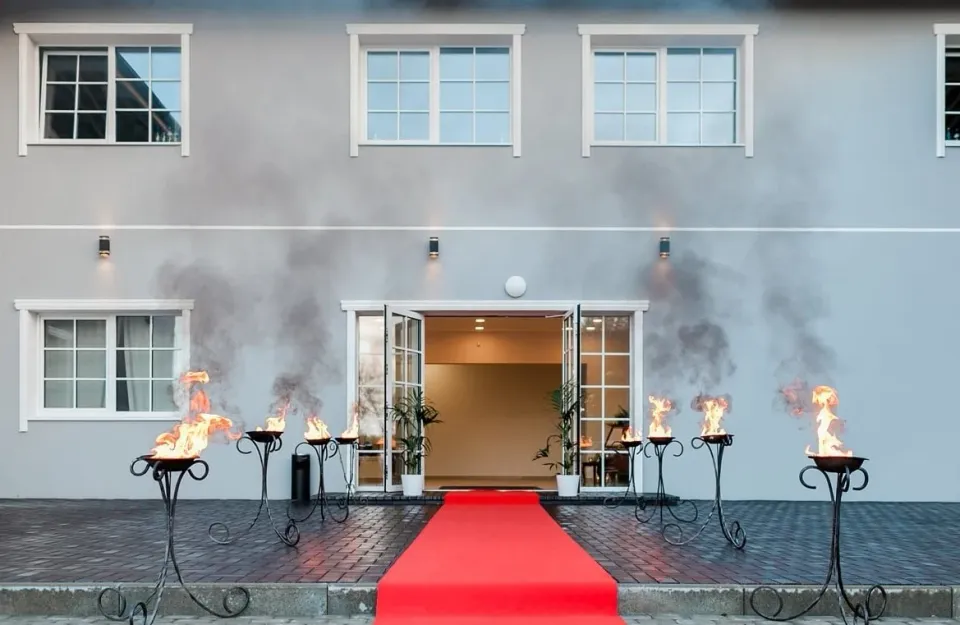 Riteriai su ietimi žengia pro degančius ugnies stovus vakaro gatvėje