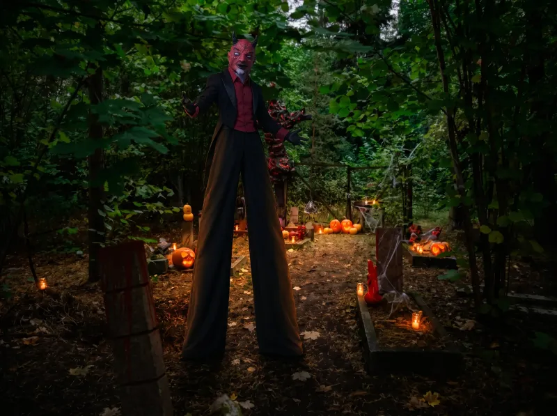 Szczudlarz w masce diabła w parku Halloween