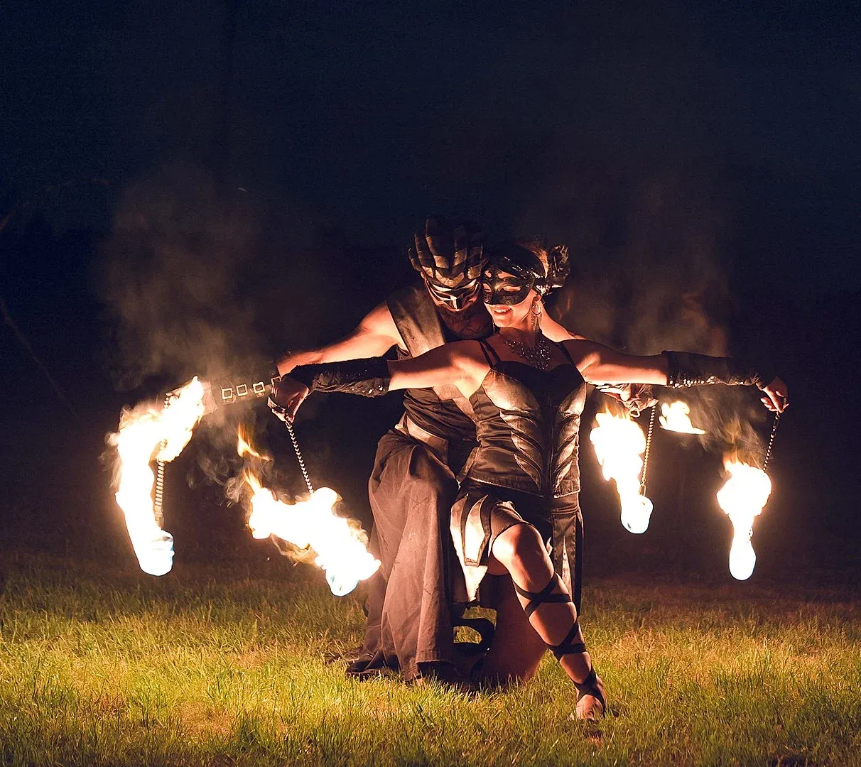 A duo in Venetian masks dances with blazing chain poi