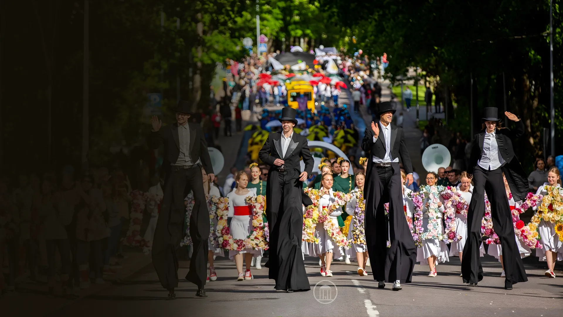 Top-hatted stilt walkers greet guests in a parade