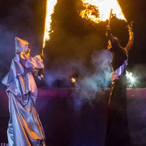 Stilt walkers with blazing swords in a night performance