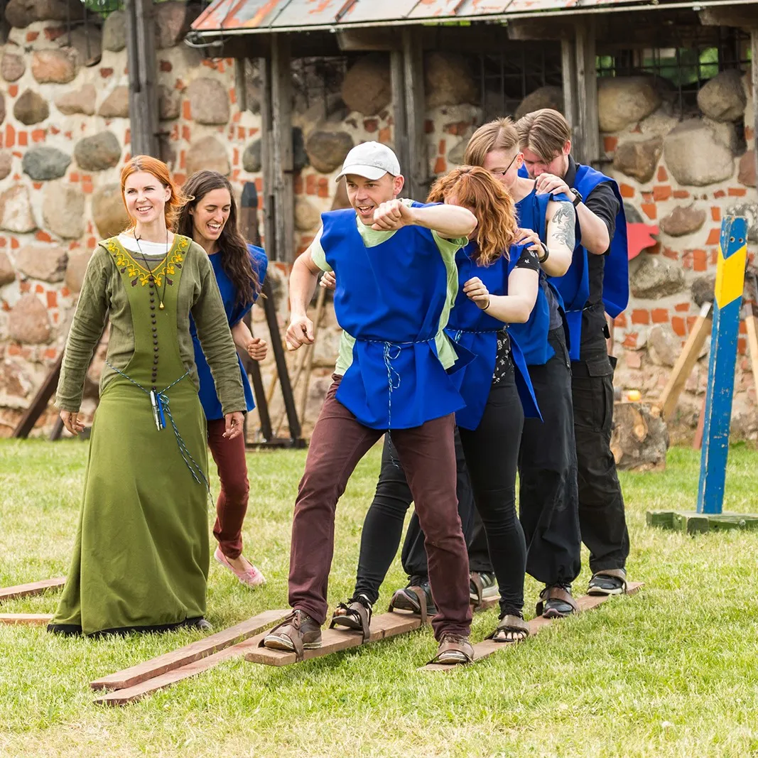 A team balances together on a wooden plank during a group challenge