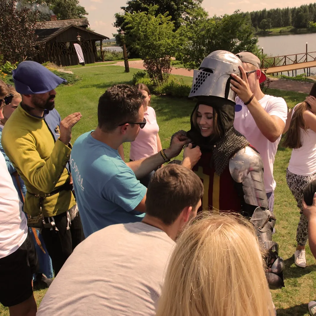 Colleagues help each other put on a knight's armour