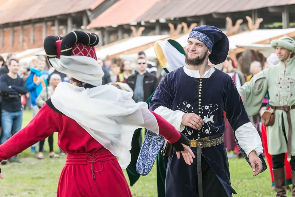 Costumed pair performing a historical dance before an audience at the castle