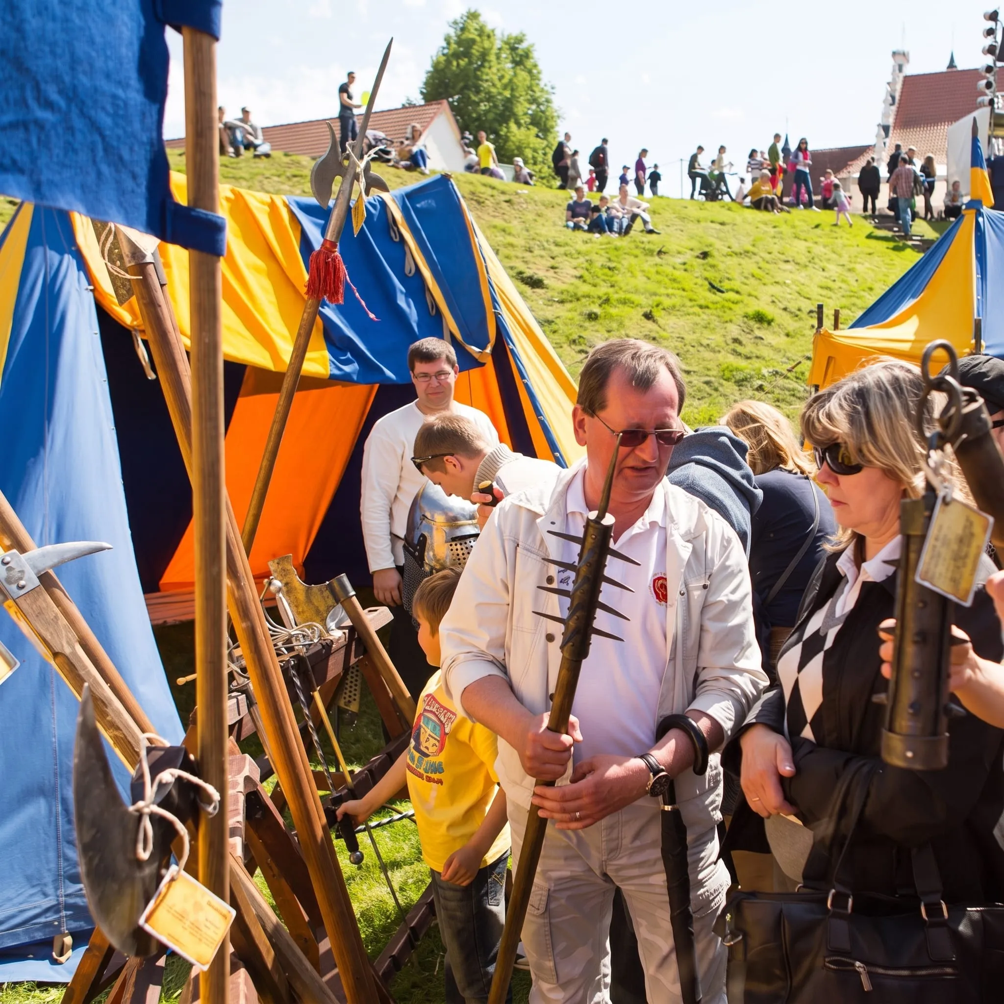 Visitors browse the weapons display among colourful tents outdoors