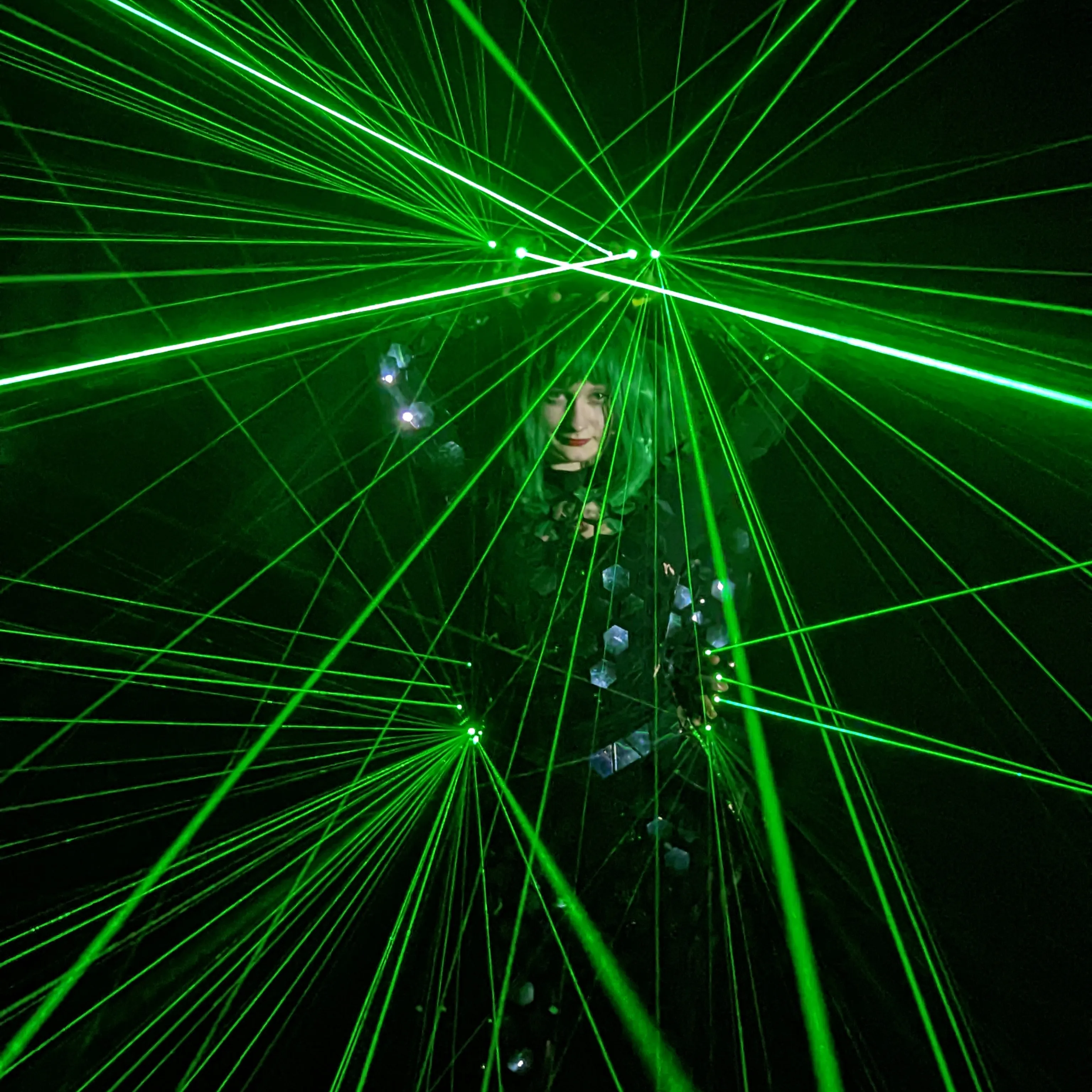 Close-up of a dancer's face amid crossing green laser lines