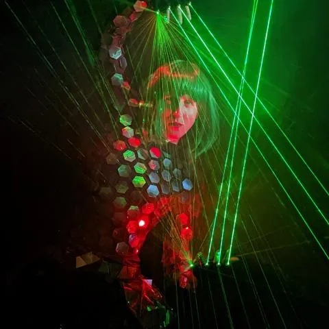 A dancer's face lit by a mix of red and green laser light