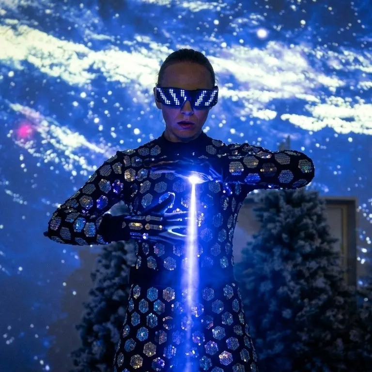 The performer controls a blue laser beam in their hand against a starry backdrop