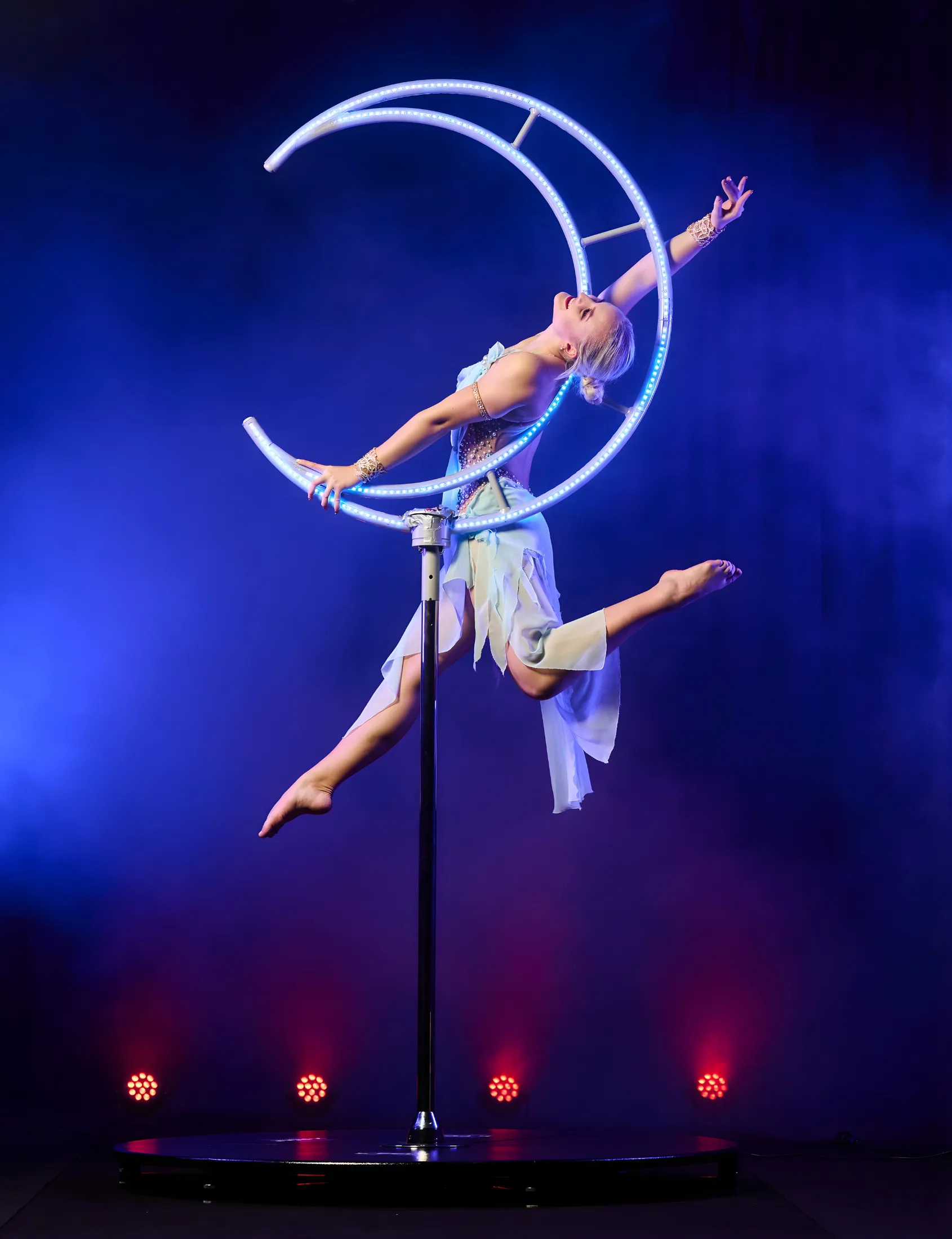 An acrobat mid-leap inside a glowing Moon-shaped LED apparatus