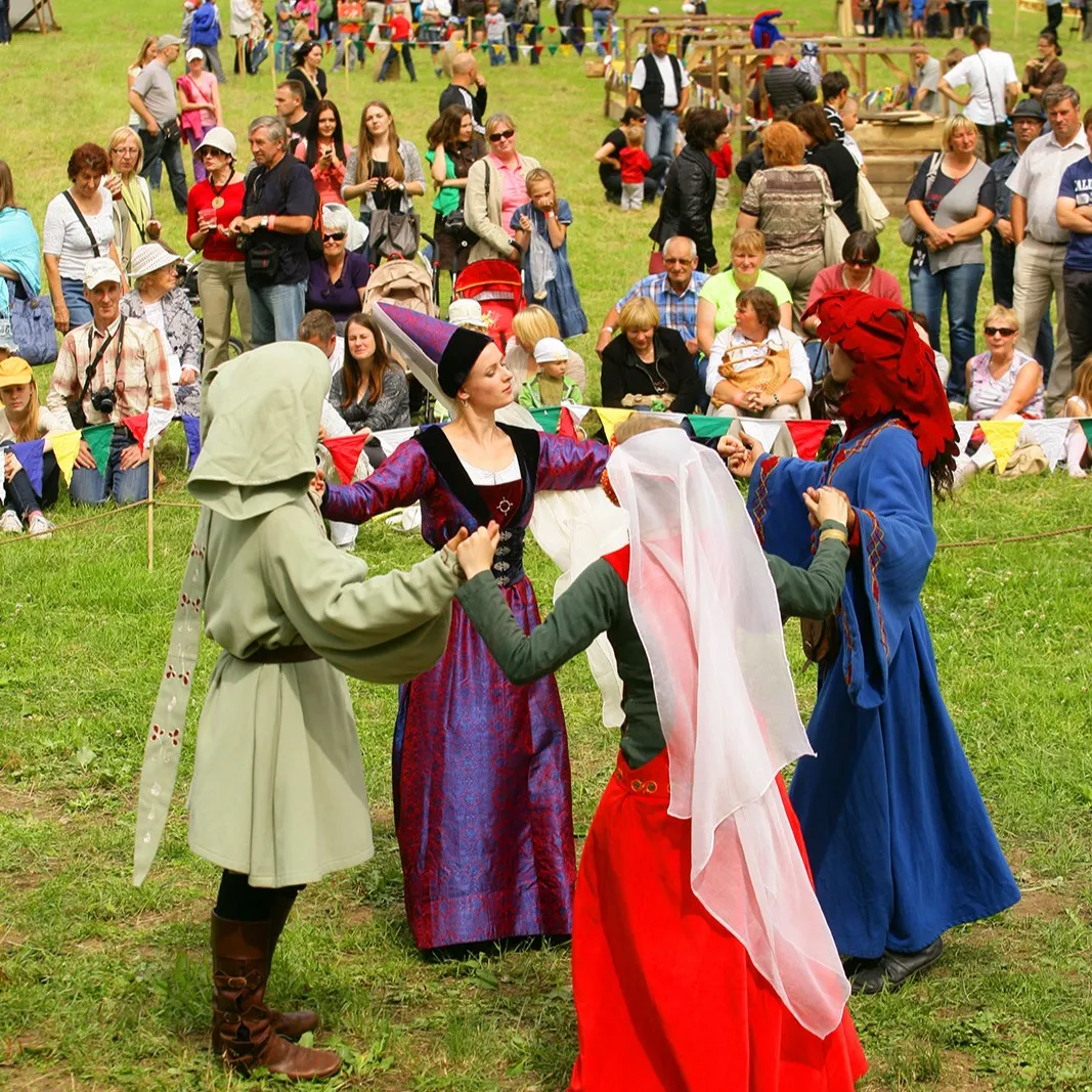 Dancers in medieval costumes turn a circle dance in front of spectators