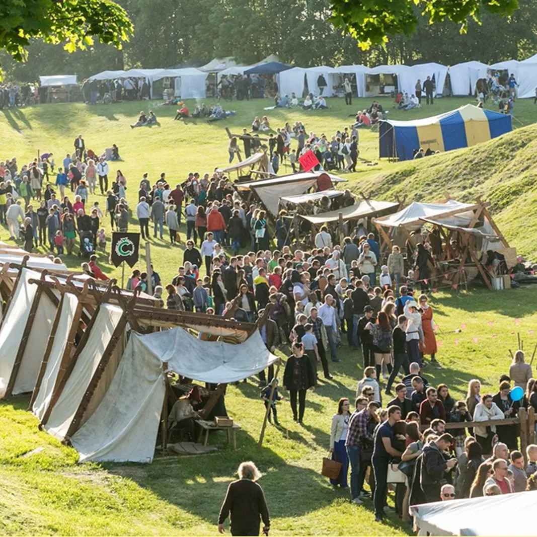 A medieval market camp with tents and a large flow of visitors