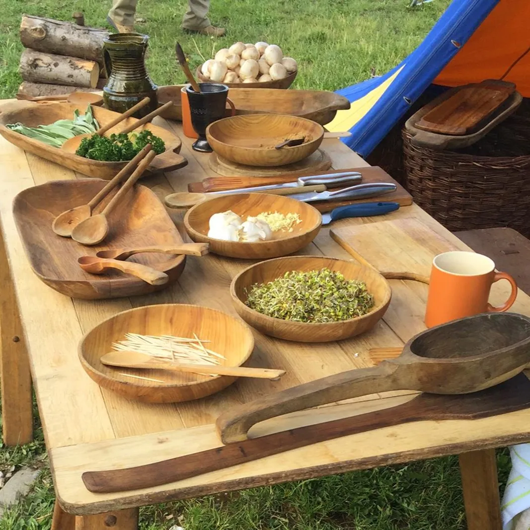 Wooden bowls and utensils set out for a medieval-style feast outdoors