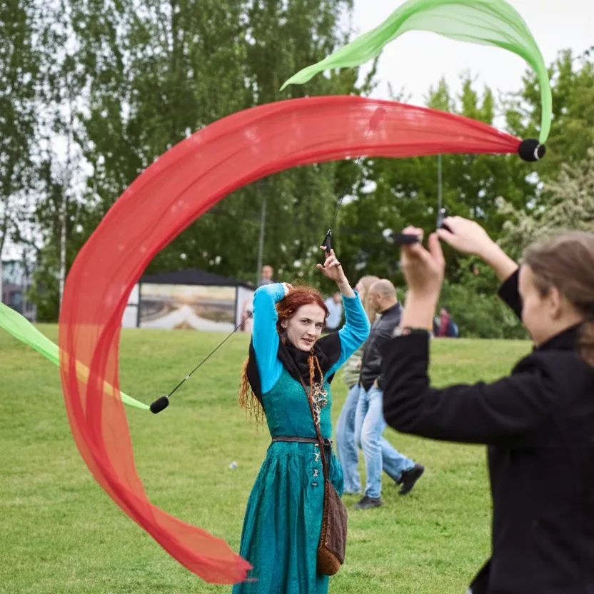 A woman spins red and green flow ribbons in a park