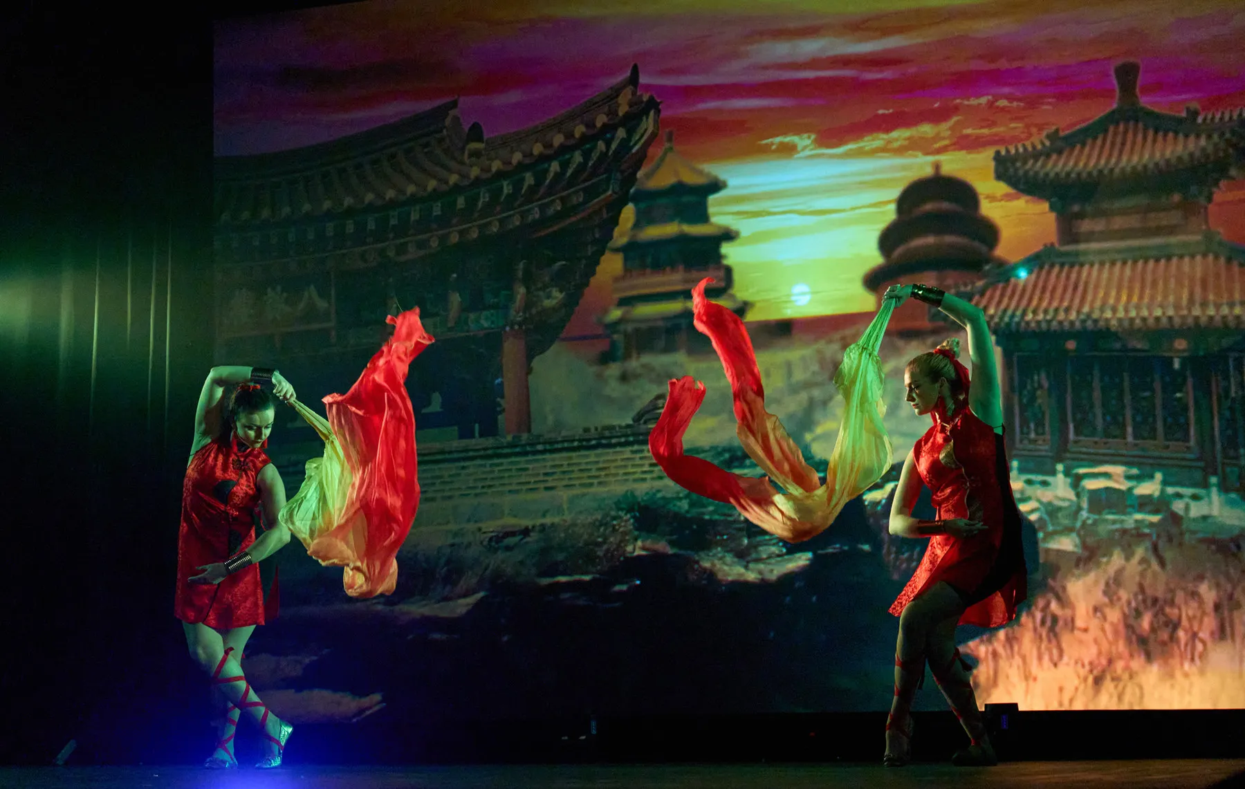 Dancers with flowing silk ribbons before a projected eastern temple