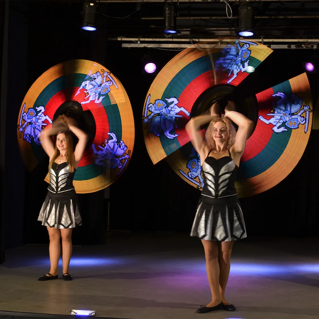 Two performers paint colourful knight figures in the air with LED hoops