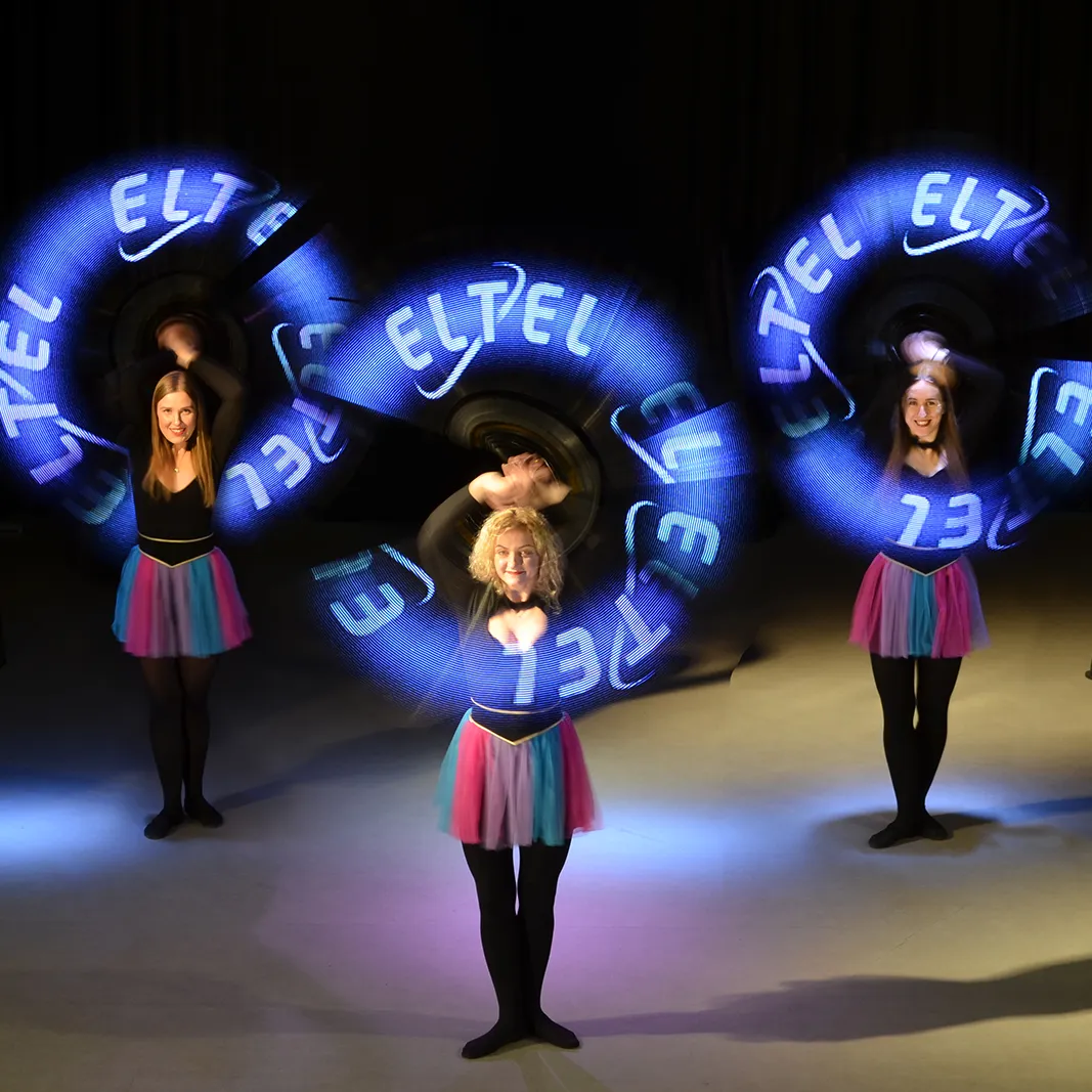Three performers use LED hoops to paint a client's company logo in the air