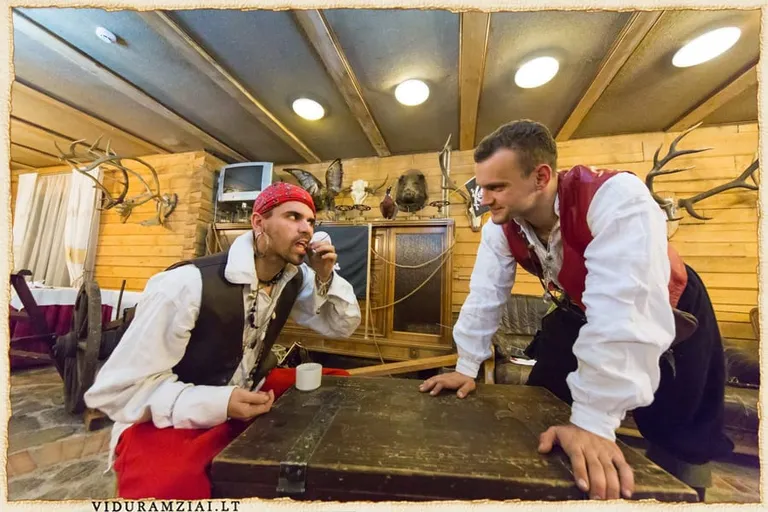 Divi pirātu tēli pie koka galda krodziņa vidē