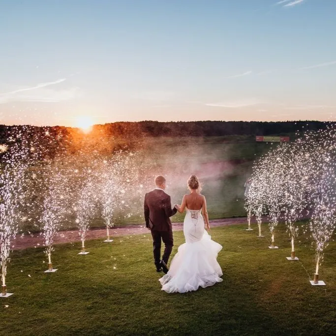 A couple walks a path lined with cold spark fountains at sunset