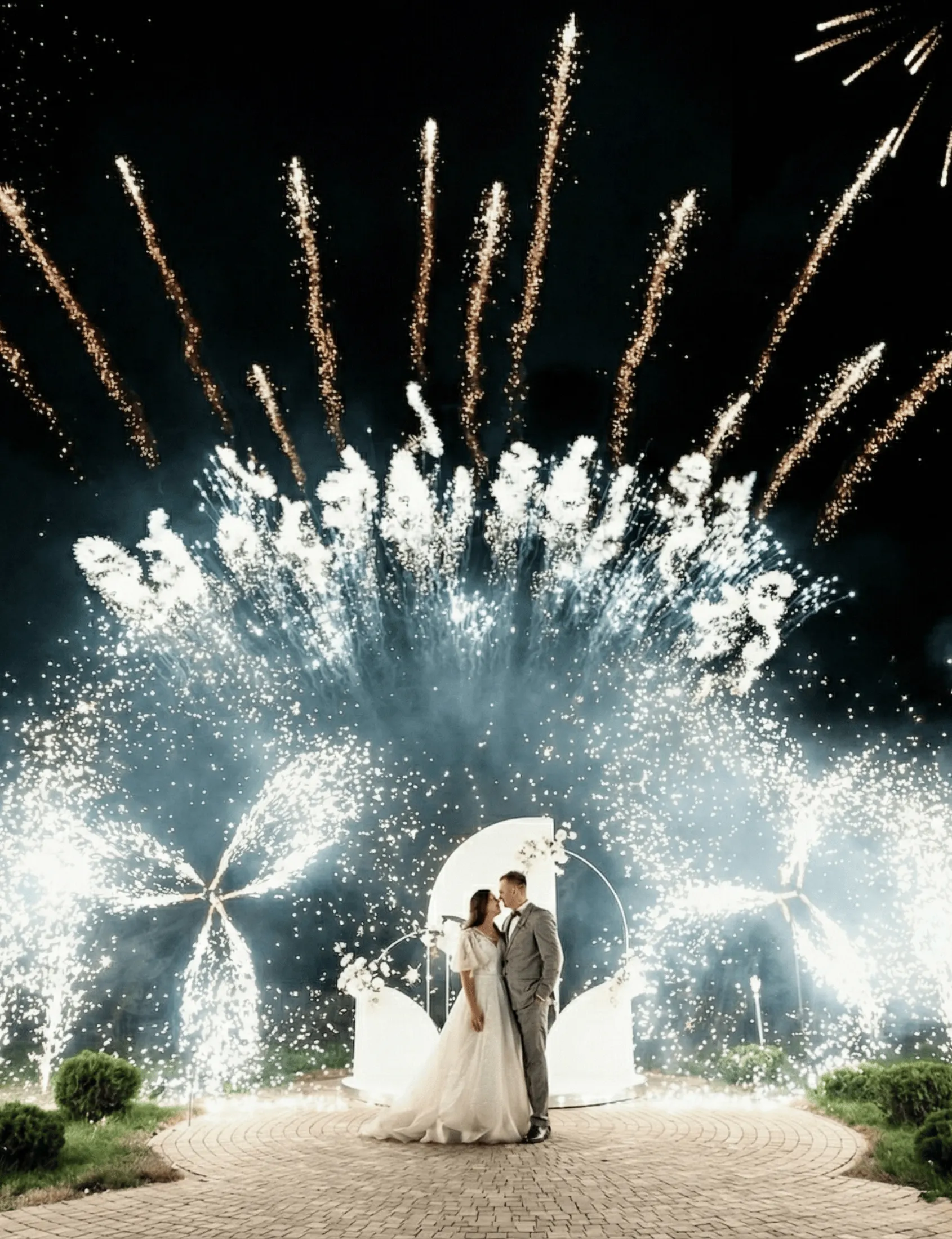Newlyweds kiss under a fireworks arch at their wedding ceremony