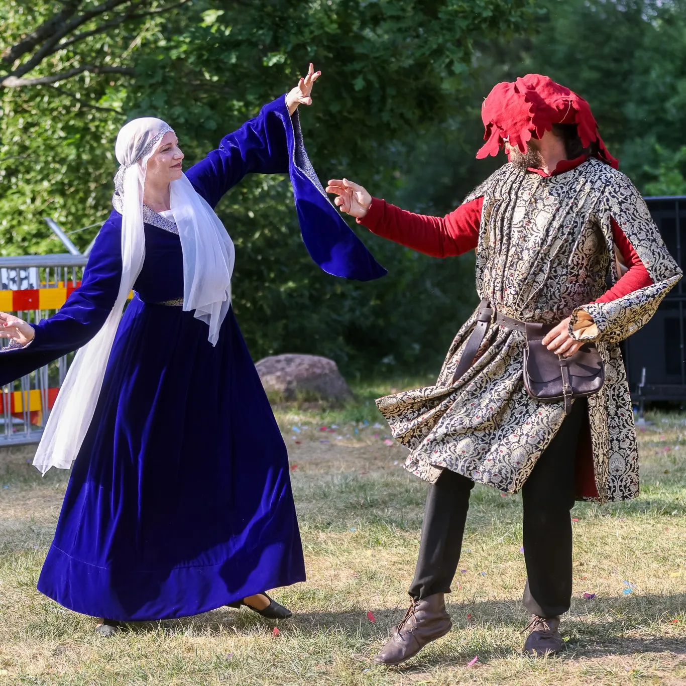 A couple in a deep-blue velvet gown dances outdoors among onlookers