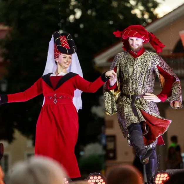 A couple dances on stage under evening lights in front of the audience