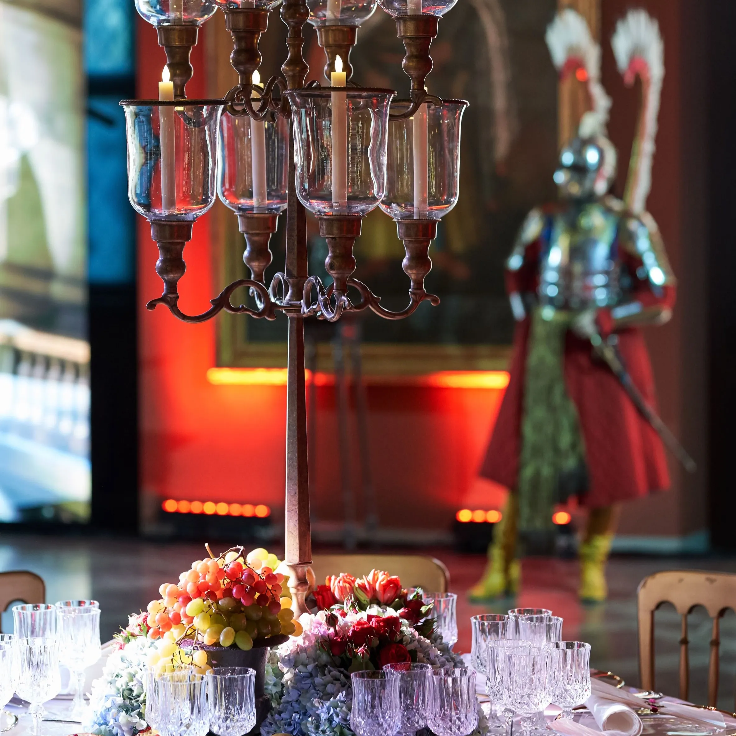 A banquet table centrepiece with candles, fruit and flowers
