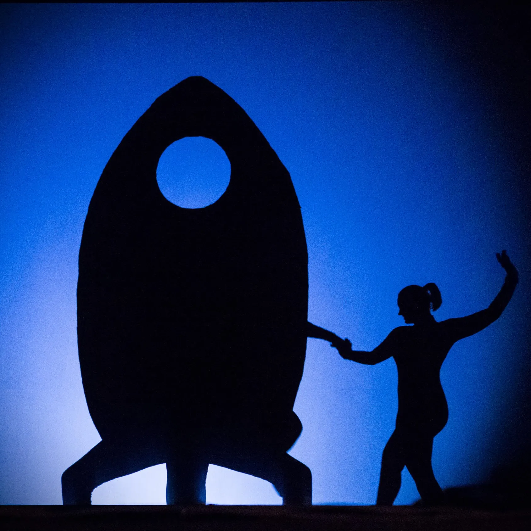 A rocket-shaped silhouette prop with a performer on the shadow-theatre stage