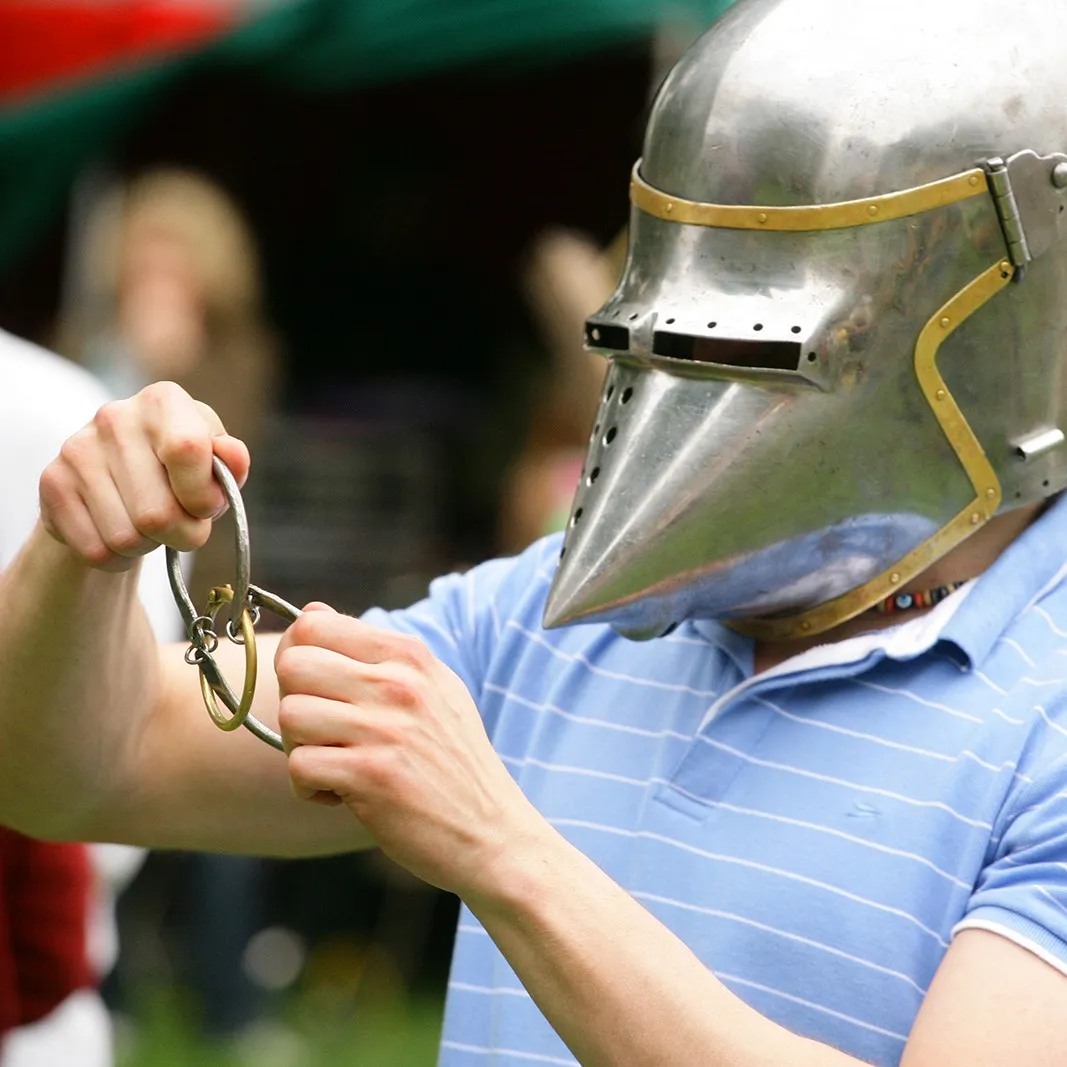 Hands attach chainmail rings to a participant's helmet
