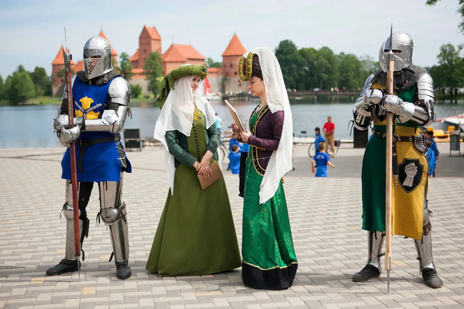 Bruņinieki un dāmas vēsturiskos tērpos pie Traķu pils ezera krastmalas