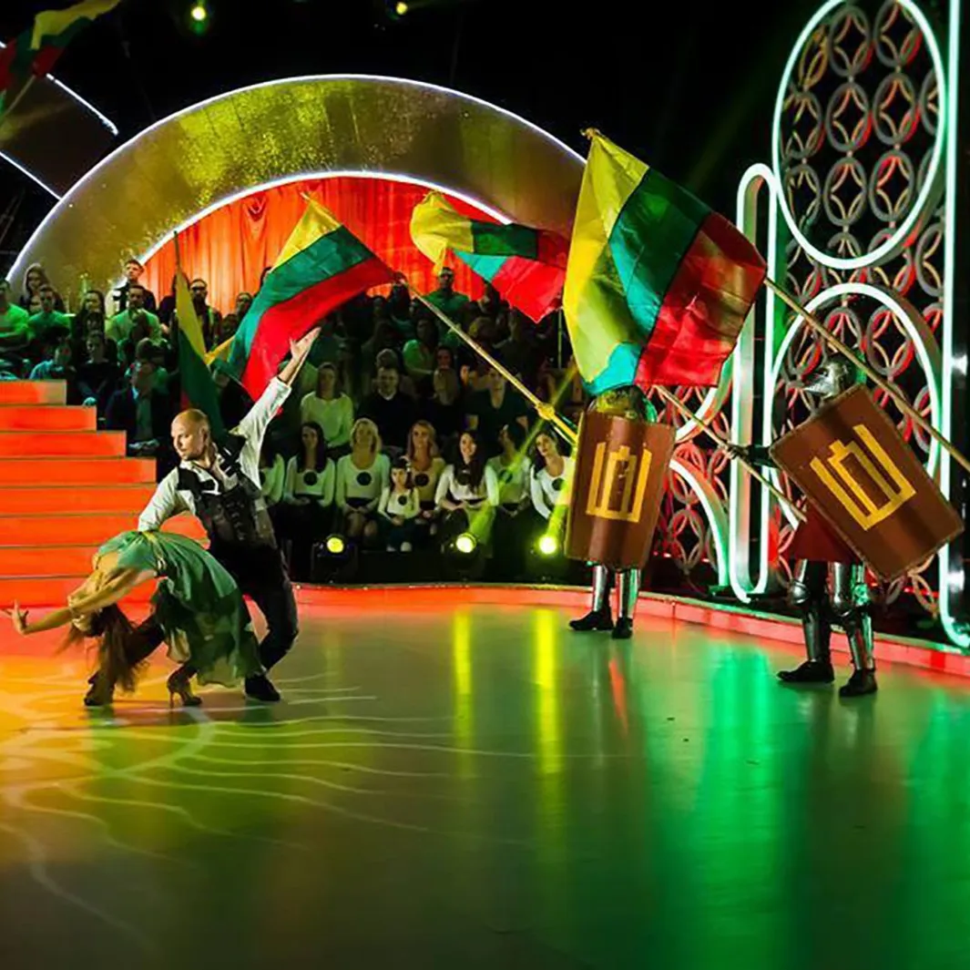 Flag-bearing knights alongside dancers on a television show stage