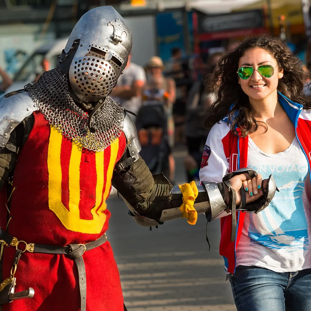 A knight in full armor walks hand in hand with an event visitor