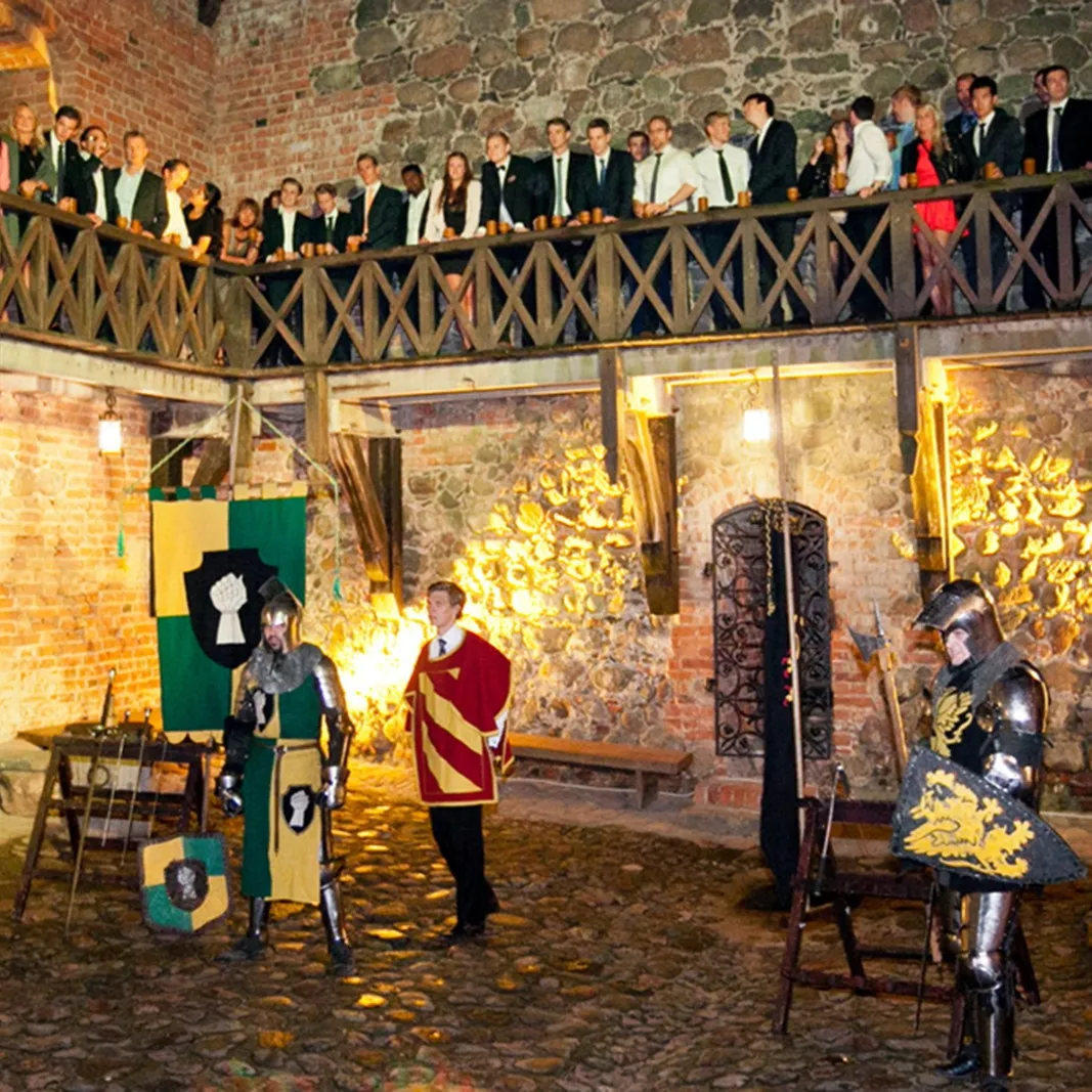 A knights' tournament in the castle courtyard, guests watch from the balcony